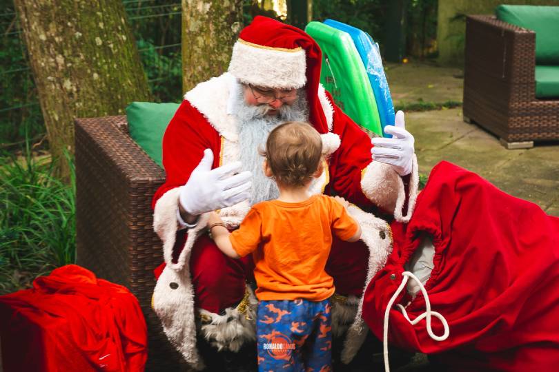 Papai Noel em uma festa de fim de ano, cercado por convidados sorridentes
