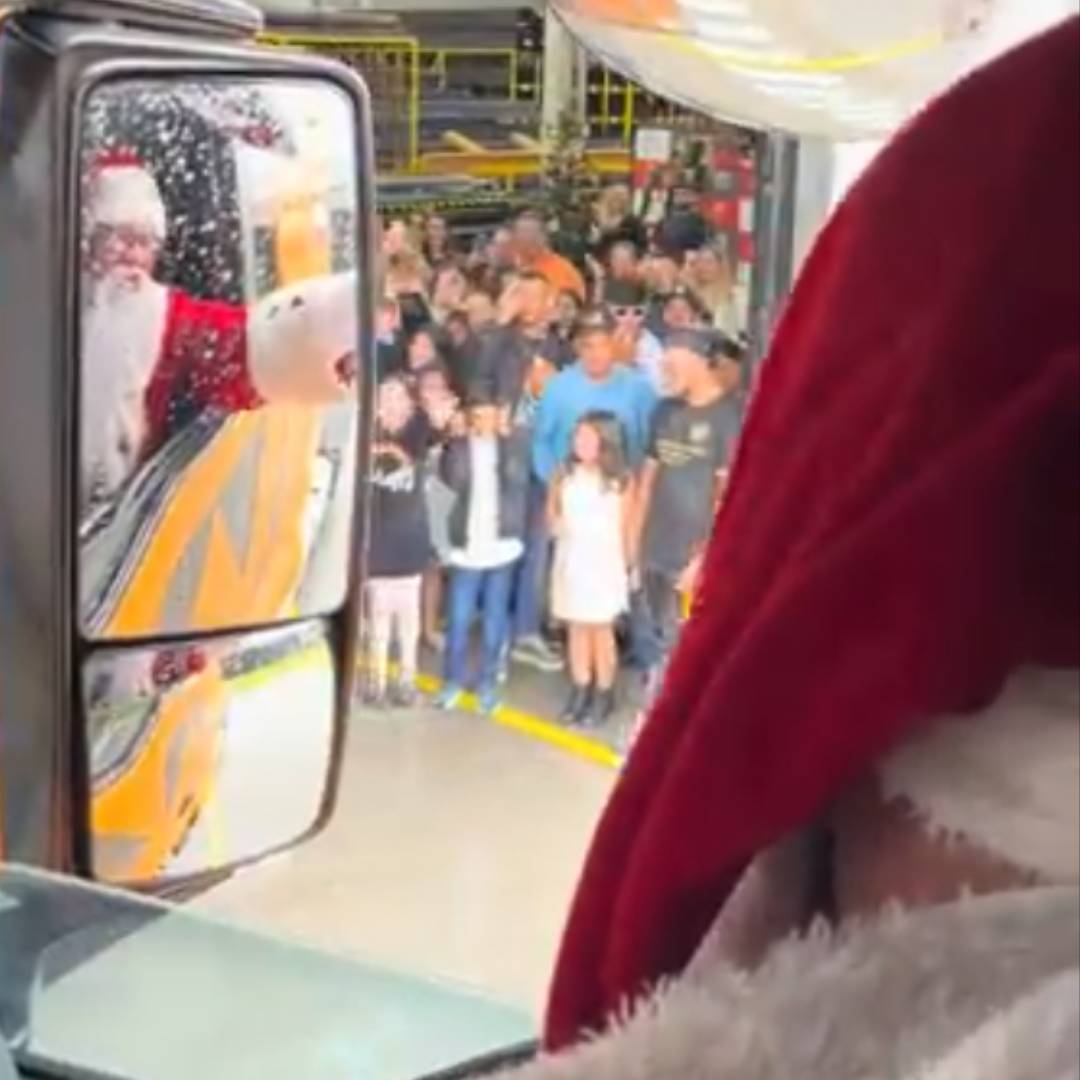 Papai Noel entregando um presente a um menino junto à lareira