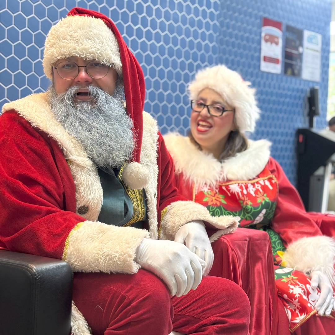 Papai Noel é a atração de uma festa corporativa, tocando pandeiro e sino