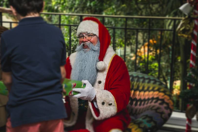 Papai Noel entregando uma caixa de presente a um menino em uma cadeira estampada