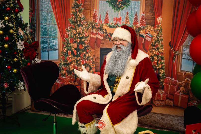 Papai Noel distribuindo presentes a dois meninos perto da árvore de Natal