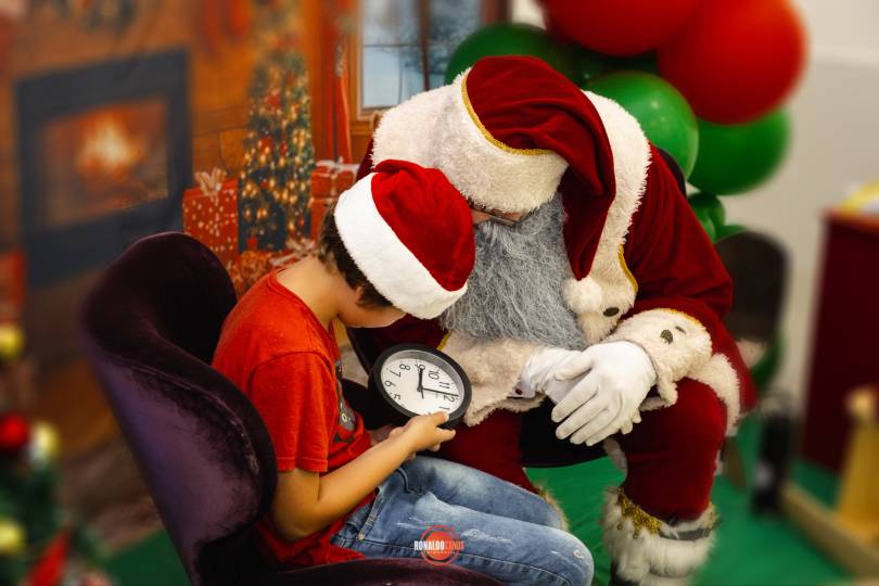 Papai Noel em um momento terno de visita especial, entre duas senhoras sorridentes